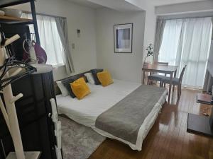 東京にあるホテルレスポワール301のベッドルーム1室(黄色い枕とテーブル付きのベッド1台付)