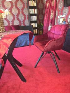 una camera da letto con una sedia rossa su un tappeto rosso di JEVA Apartman a Hajdúszoboszló
