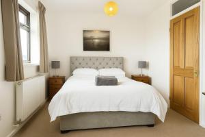 Un dormitorio con una cama grande con sábanas blancas. en Wheal Francis - Hot Tub - Accessible Bungalow - Free Wi-Fi - Parking, en Helston