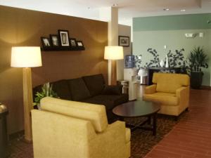 Una sala de estar con un sofá y dos sillas y una mesa. en Sleep Inn & Suites Syracuse Airport, en East Syracuse