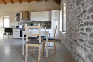 a kitchen with a table and chairs and a stone wall at Villa Il Circolo Bassone in Pontremoli