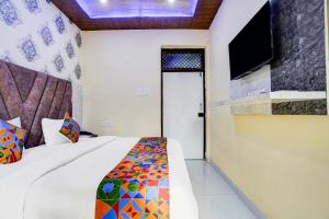 a bedroom with a bed and a tv on the wall at FabHotel Ratraksh in Kānpur +21 photos