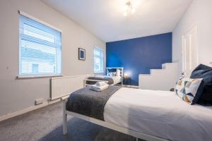 a bedroom with a bed and a blue wall at Tŷ Glas by Tŷ SA in Newport