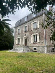 an old brick house with a grassy field in front of it at Chateau Le Vieil Etang in Saint-Sauveur-le-Vicomte