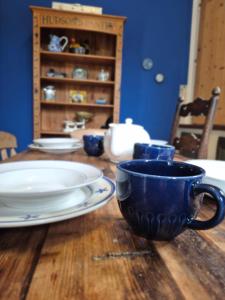 a wooden table with blue cups and plates on it at Chateau Le Vieil Etang in Saint-Sauveur-le-Vicomte