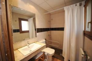 Un baño con lavabo, inodoro y espejo. en Gran Casa de Montana, en Fornells de la Muntanya