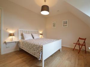 ein Schlafzimmer mit einem weißen Bett und einem Stuhl in der Unterkunft Sint-Amands Country Escape in Sint-Amands