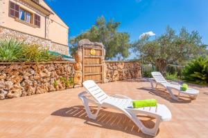 two white chairs on a patio with a stone wall at Can Kalet in Costitx