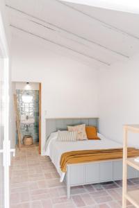a bed in a room with a white wall at Casa Majú - Algarve in Valados