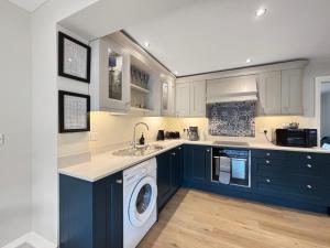 a kitchen with blue cabinets and a washer and dryer at Amaya Eleven - 3 bed cottage in village in Harlaxton +14 photos