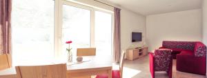 アーレンゼーにあるFerienhaus Friedrichsmildeのリビングルーム(赤いソファ、テーブル付)