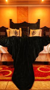 a bed with a black comforter on top of it at Phumelela Guesthouse in Trompsburg