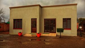 a white building with red pots in front of it at Phumelela Guesthouse in Trompsburg