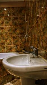 a white sink in a bathroom with a tiled wall at Phumelela Guesthouse in Trompsburg