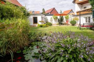 a garden with a pond and flowers in front of a house at Lux Ferienwohnung altes Landwarenhaus mit Garten und zubuchbarer Sauna in Hedersleben