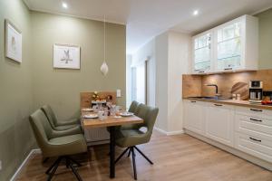 a kitchen with a wooden table and green chairs at Lux Ferienwohnung altes Landwarenhaus mit Garten und zubuchbarer Sauna in Hedersleben