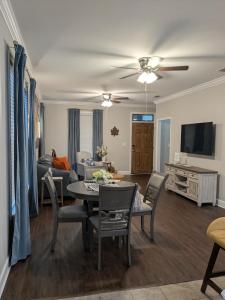 un salon avec une table, des chaises et une télévision dans l'établissement Serenity Cottage, à Thomasville