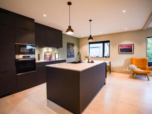 a kitchen with black cabinets and an orange chair at Central apartment in Tromsø