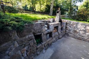 Un muro de contención de piedra con una campana en él. en Dom Zielony Kamień z jacuzzi i bilardem, en Szklarska Poręba