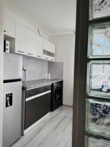 a kitchen with white cabinets and a black dishwasher at Relax House El Passo in Târgu-Mureş +7 photos