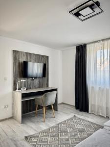 a hotel room with a desk and a television at Relax House El Passo in Târgu-Mureş