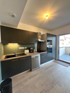 een keuken met grijze kasten en een groot raam bij Appartements Prestiges I Draps&ménage inclus I parking privé in Saint-Lary-Soulan