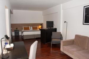 a bedroom with a bed and a couch and a table at Duomi Hotel Buenos Aires in Buenos Aires