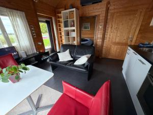 a living room with a black leather couch and red chairs at Cottage Nieuwkoop in Nieuwkoop