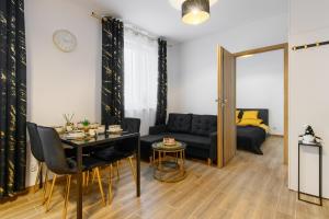 a living room with a black couch and a table at Gicek Apartament 15A bezpłatny PARKING Faktura VAT 4 osobowy K-S SSE in Gorzów Wielkopolski +8 photos