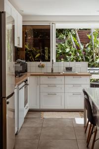 a kitchen with white cabinets and a large window at La villa Selah **** in Saint-Louis