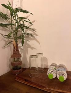 a wooden table with two glasses and a potted plant at Hotel Chingari Pinnawala in Rambukkana