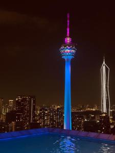 a tower lit up in blue and purple at night at Platinum Tokyo Suites by KLCC city in Kuala Lumpur
