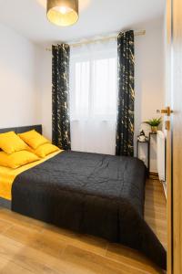 a bedroom with a black bed with yellow pillows and a window at Gicek Apartament 15B bezpłatny PARKING Faktura VAT 4 osobowy K-S SSE in Gorzów Wielkopolski