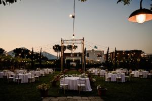 a wedding reception with white tables and chairs and lights at Resort & Winery Bosco De Medici in Pompei +165 photos