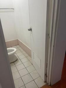 a white bathroom with a toilet and a door at Cherry Traveller Inn in San Jose de Buenavista +3 photos