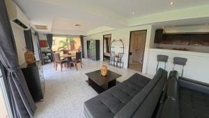 Una sala de estar con un sofá y una cocina. en Condominium Rawai D1 - near convenience beach, market, gym, en Ban Saiyuan (1)