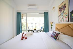 a bedroom with a large white bed with two dolls on it at Cloud Line by Leo Homes - 2BHK near Anjuna Beach in Anjuna +44 photos