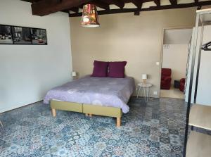 a bedroom with a bed with purple pillows on it at Gîte Du Moulin Béchereau in Mer