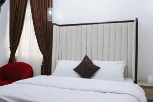a bedroom with two beds and a red chair at Hometime Utako in Abuja