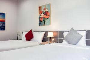two beds in a hotel room with white and red pillows at Sunshine Hotel in Buon Ma Thuot +4 photos