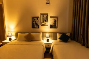 two beds in a room with two lamps at Sunshine Hotel in Buon Ma Thuot