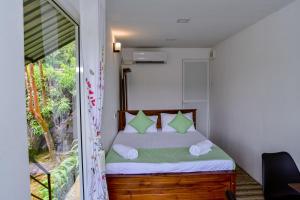 een slaapkamer met een bed met groene kussens en een raam bij Mist of Sinharaja in Galle +61 foto's