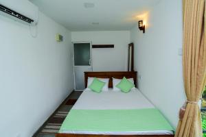 Un dormitorio con una cama con almohadas verdes. en Mist of Sinharaja, en Galle
