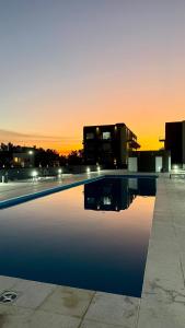 a swimming pool in front of a building at sunset at Confort y Cercania Ezeiza in Ezeiza