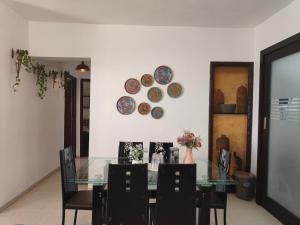 a dining room with a glass table and chairs and plates on the wall at Staeg Skyline View 3BHK - 1404 in Indore