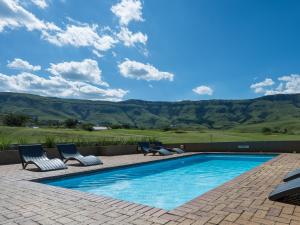 a swimming pool with chairs and mountains in the background at ANEW Resort Vulintaba Newcastle in Newcastle