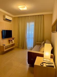 een slaapkamer met een bed, een televisie en een bureau bij Flat Mont Blanc Premium in Ribeirão Preto