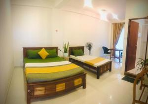 a bedroom with two beds and a table at Golden King Residence Kandy in Kandy
