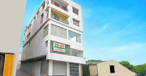 a white building with a sign on the side of it at The Crown Inn Madhyamgram in kolkata