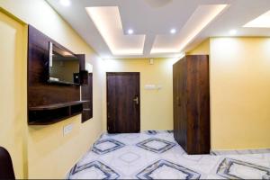 a room with two doors and a tv on the wall at The Crown Inn Madhyamgram in kolkata
